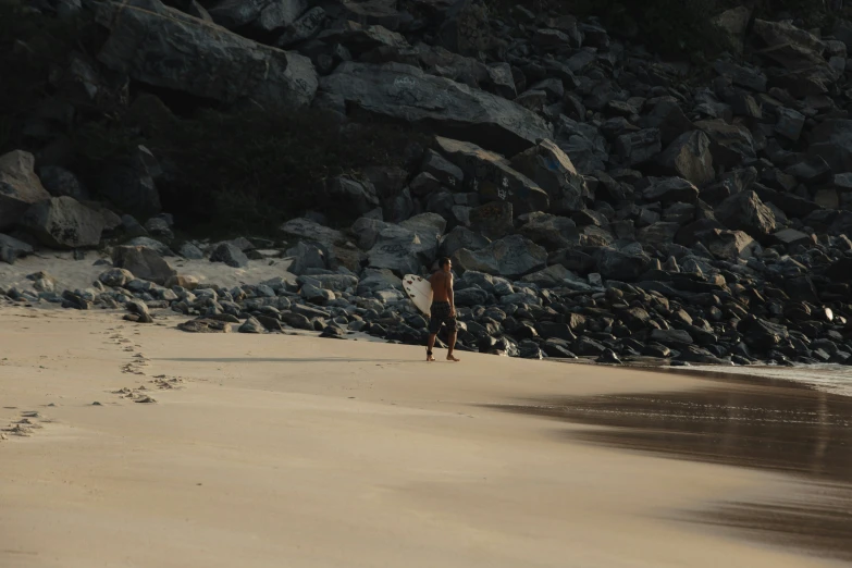 there is a man walking on a beach with a frisbee