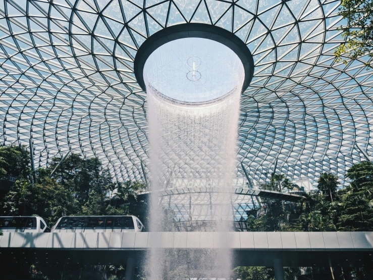 a large, glass structure with a fountain spewing water