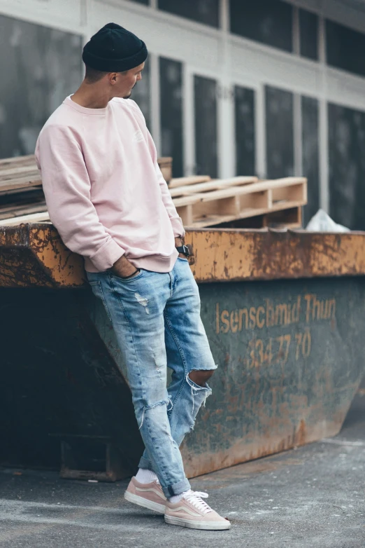 a young man is standing next to an empty dumpster