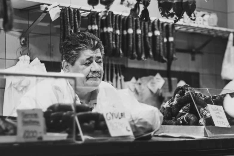 an older woman stares at the camera in front of a vendor