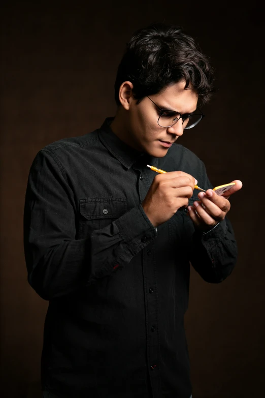 a man that is wearing glasses and holding a pen