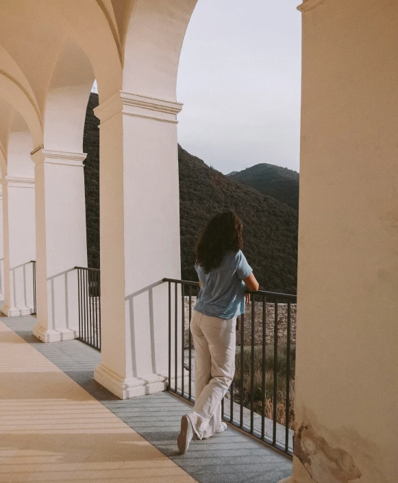 a woman walking towards an archway with a balcony