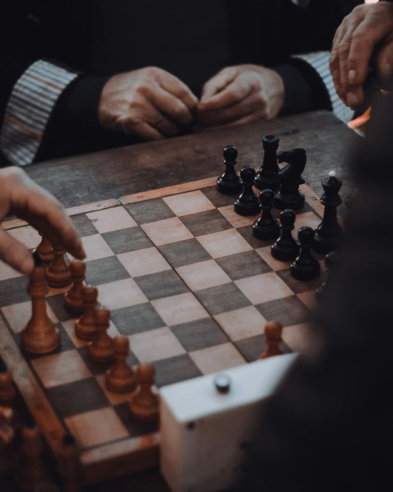 a person with their hands on the chess board