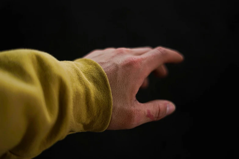 a person's hand with very long nails and a yellow shirt