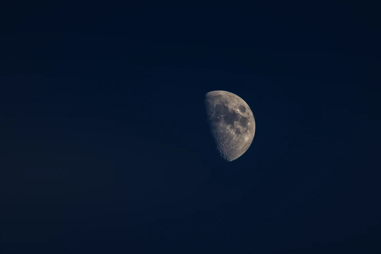 a half moon is seen through the blue sky