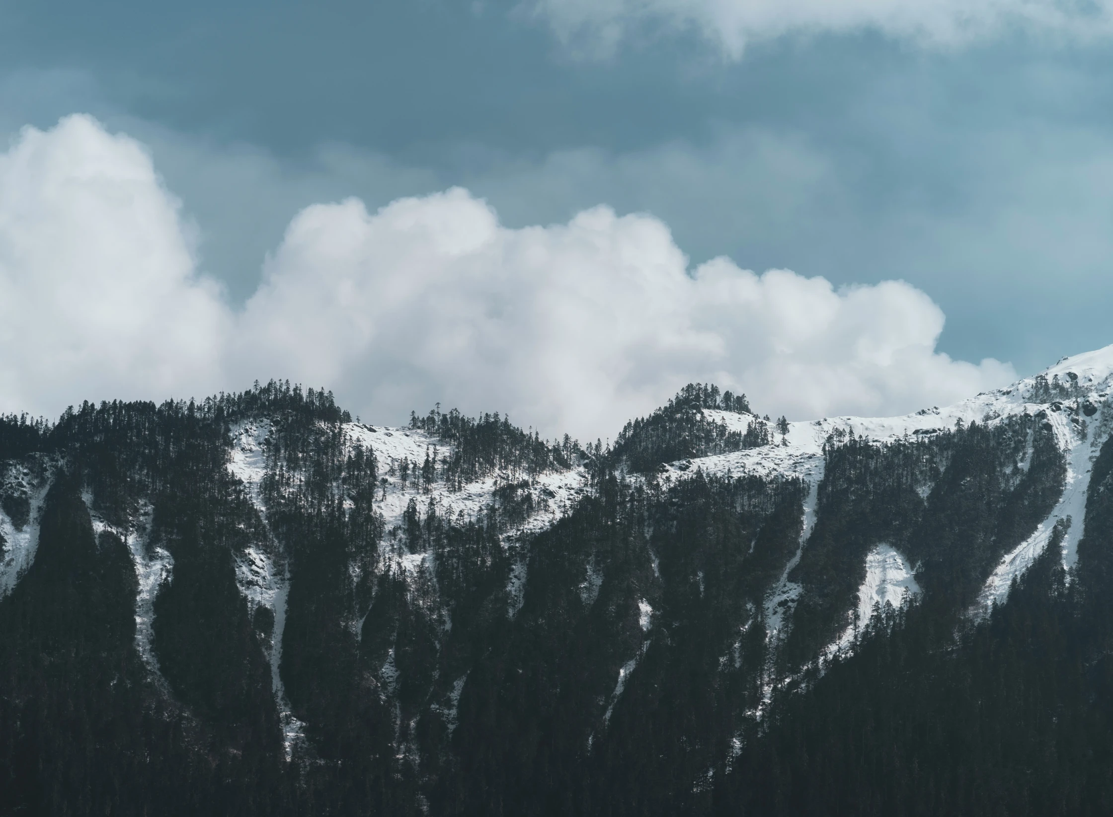 mountains covered in snow are under a cloudy sky