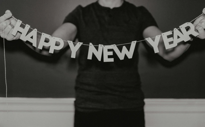 black and white pograph of a person holding a happy new year banner