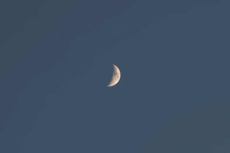 a half moon is seen with the dark blue sky