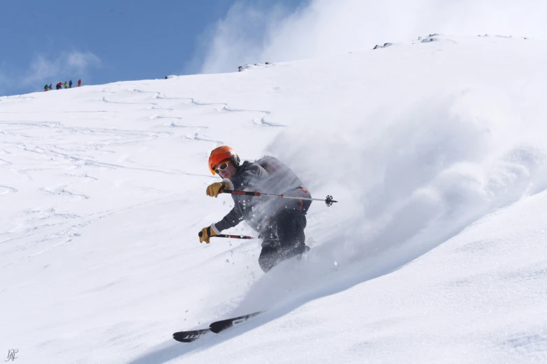 the man skiing down a hill with dust coming out of it