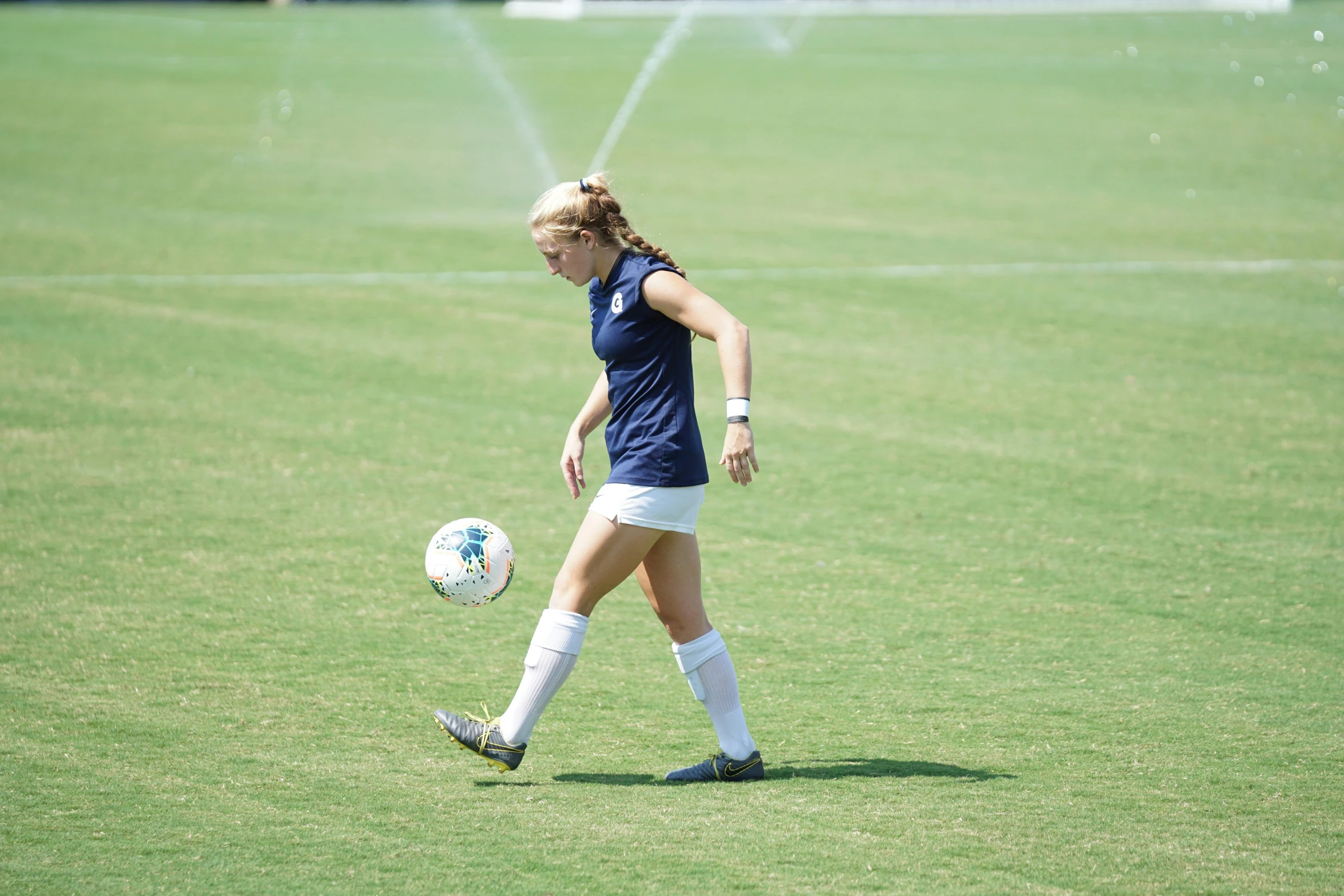 a girl in a soccer uniform is on the field playing with a soccer ball