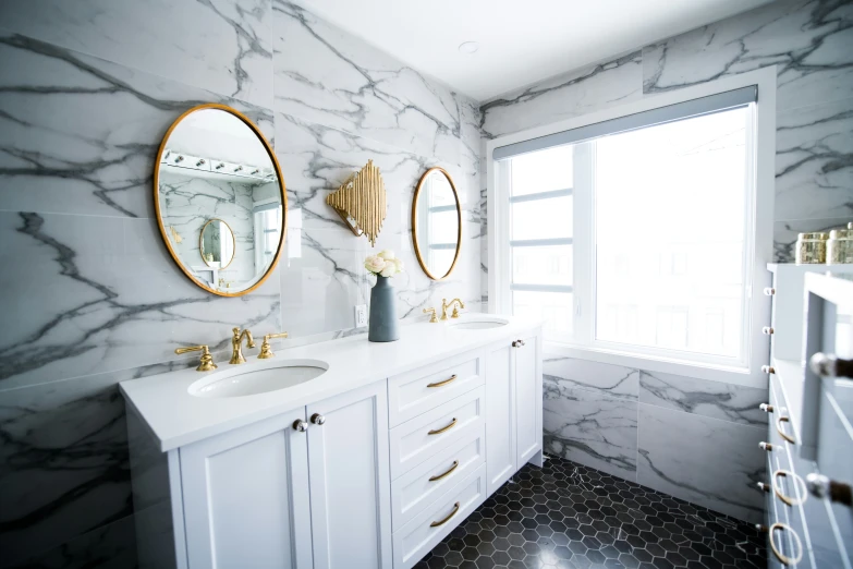 a bathroom with two mirrors on the wall and a white vanity with marble countertops