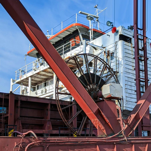 the side of a cargo ship with a large rusty water wheel