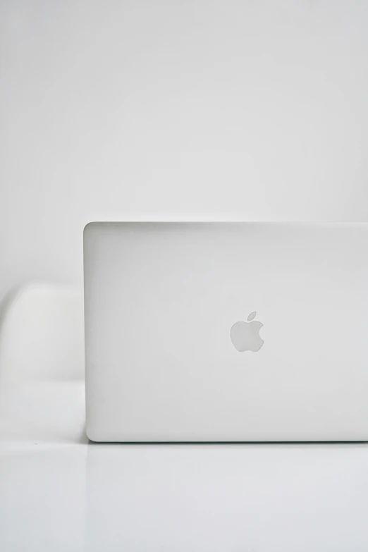 an apple laptop sitting on a white surface