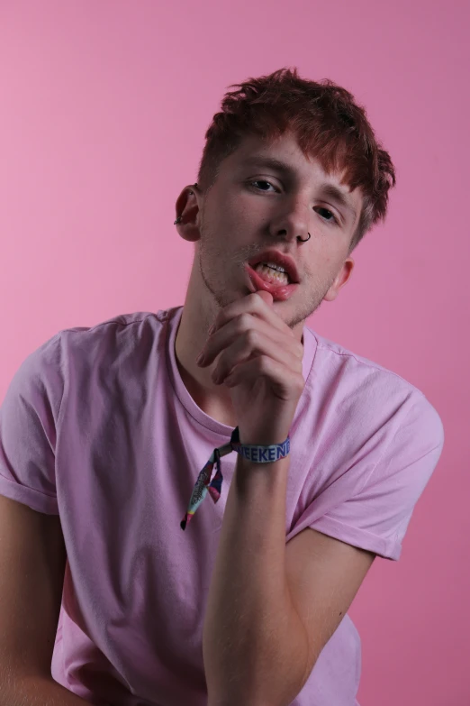 a young man in a pink shirt looks at the camera