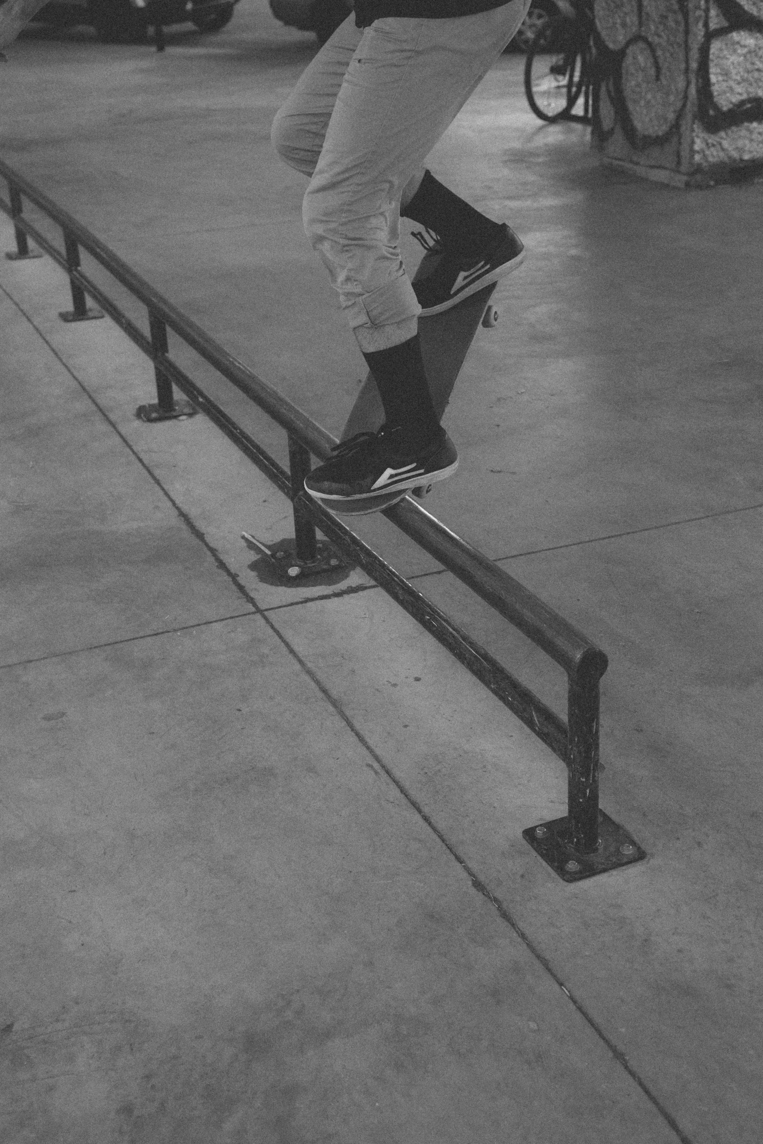 man performing skateboard trick on railing with bicycle in background