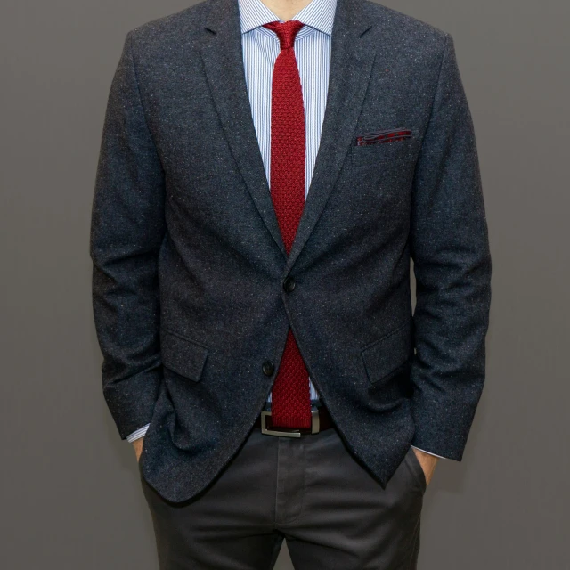 a young man wearing a suit standing in front of a wall