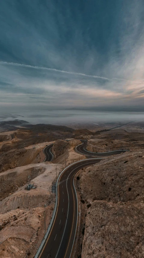 an empty road passes over a sandy mountain landscape