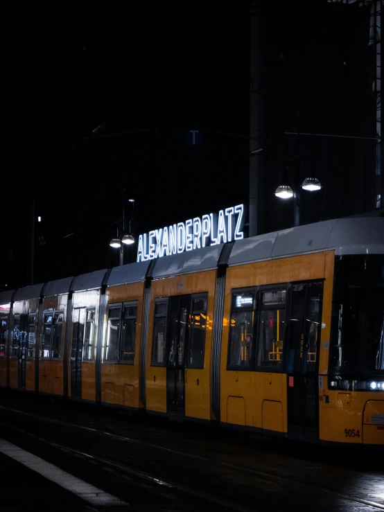 a yellow train driving on the track with lighted lights