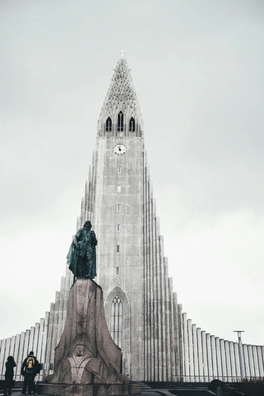 a giant tower with a clock on top and an old statue sitting in the middle of it