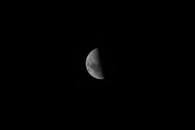 a half - moon in the sky during a dark night