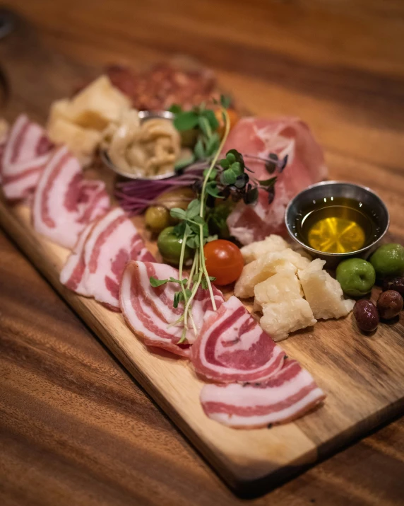 a wooden board with meats, olives and bread on it