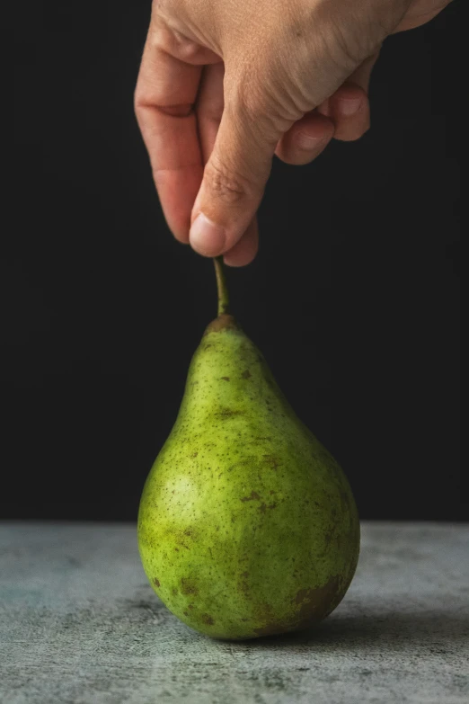 a person picking the top of a pear with one hand