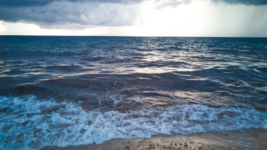 ocean waves with sunbeams in distance and the beach area is dirty