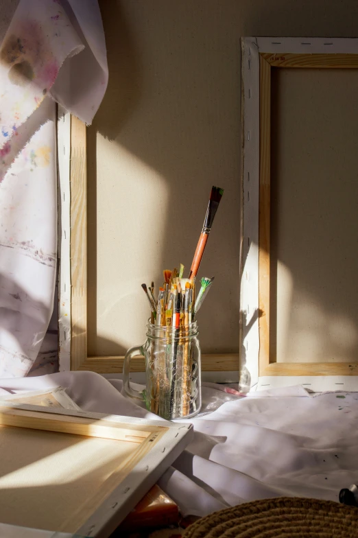 pens, paper, and other art supplies sit on top of a table in a sunny corner