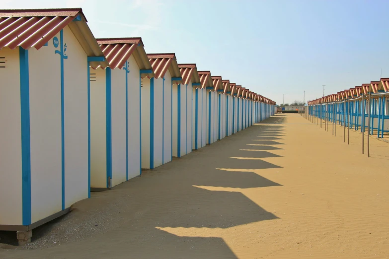 row of beach huts on a sandy beach with a blue sky