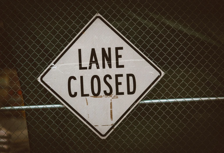 a lane closed sign is mounted to the side of a fence