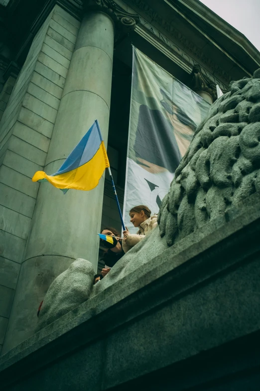 a blue and yellow kite flies above some statues