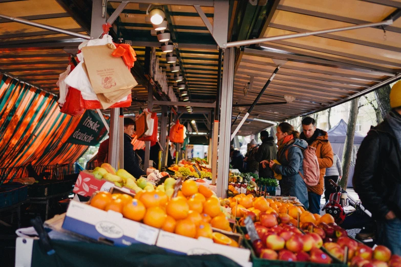 people shopping and waiting around in an outdoor produce market