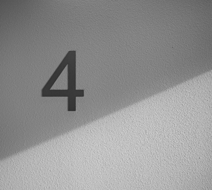 a number 4 is placed on top of a textured wall