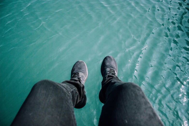 person standing in front of water looking down at the ground