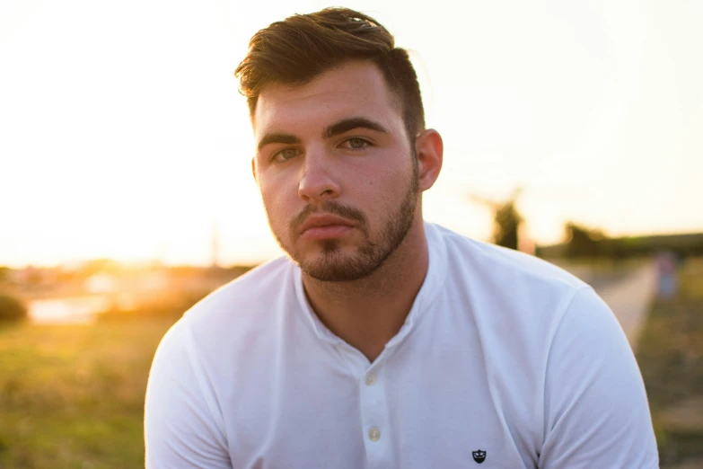 man sitting in a field at sunset looking to his left