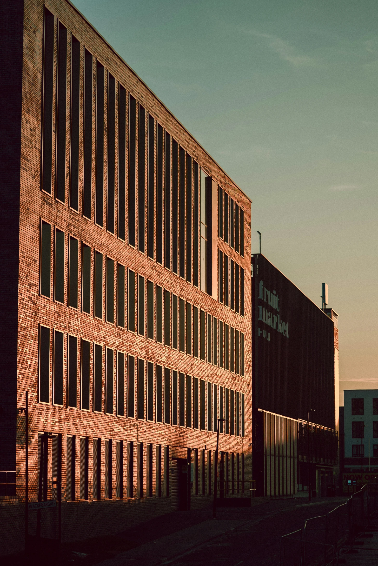 large brick building with an arched pattern and a train crossing