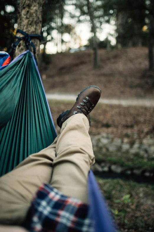 a man laying in a hammock on top of a green blanket