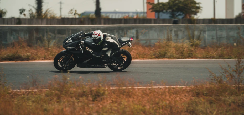 a motorcyclist turning a corner in front of an unpaved street