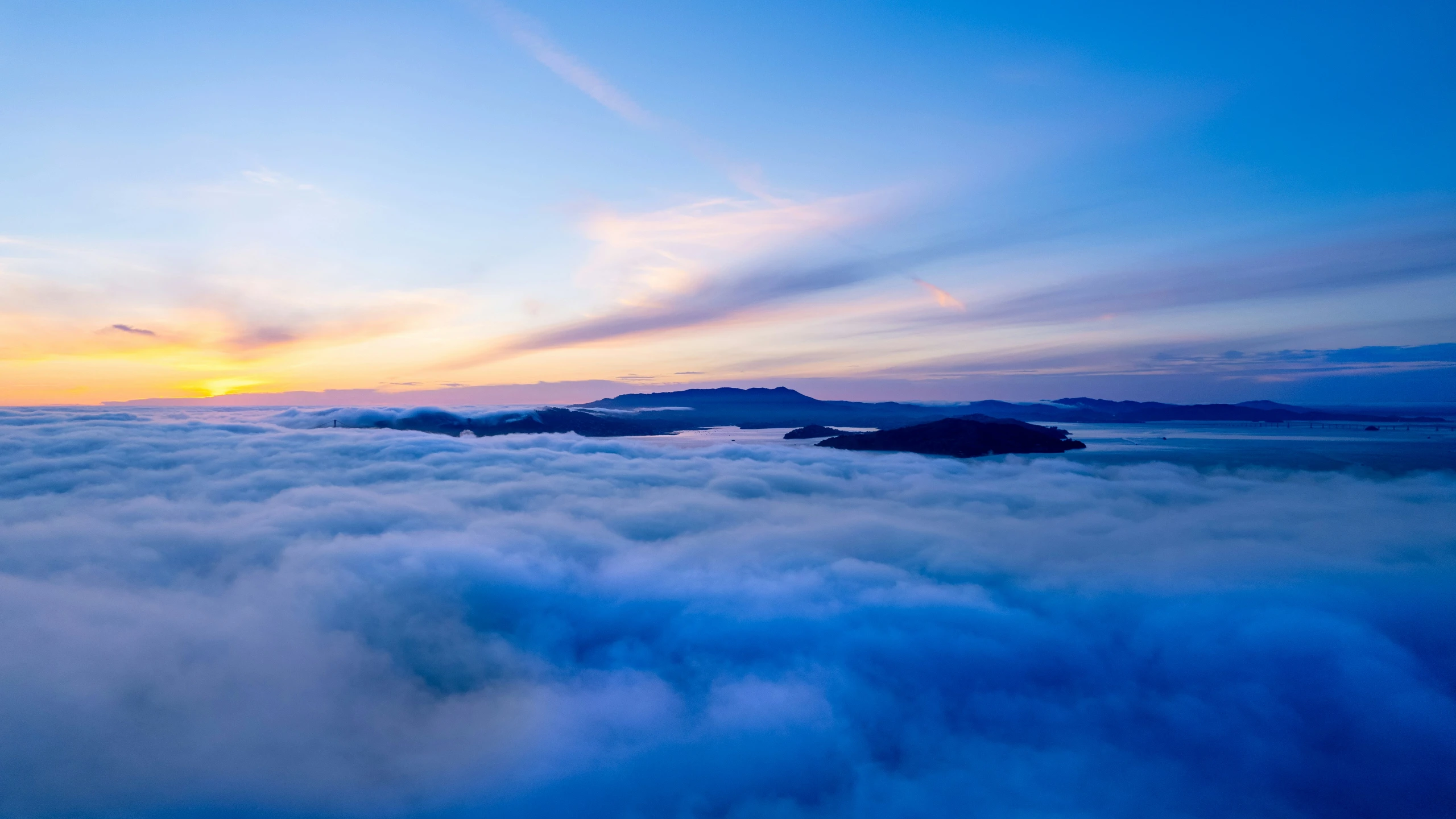 the sun rises above a sea of clouds