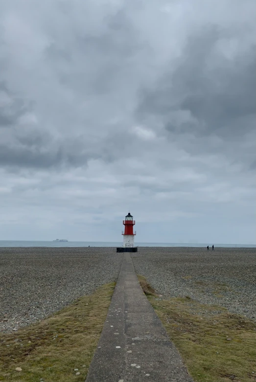 the path leads to the lighthouse on top of a cloudy day