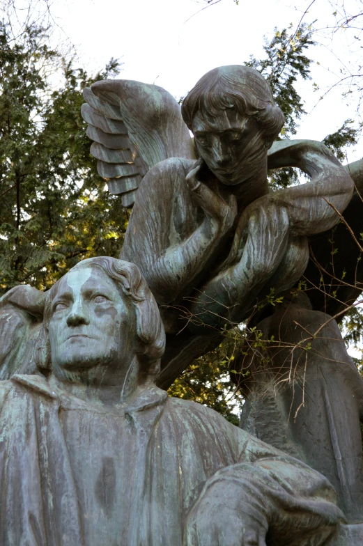 a bronze statue of an angel sitting next to a man