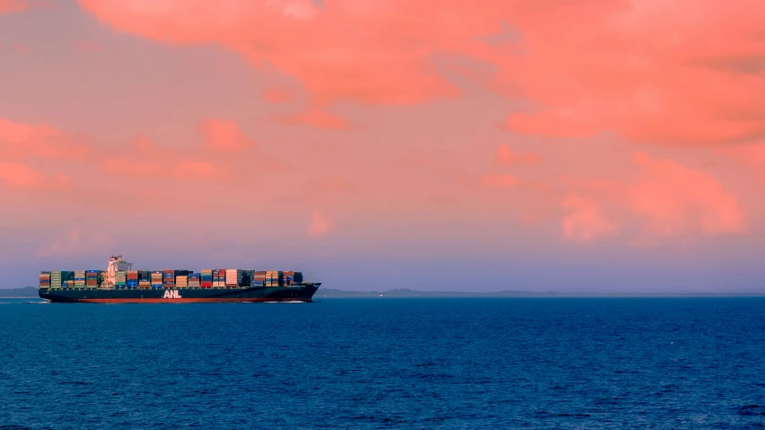 a cargo ship in the water and clouds