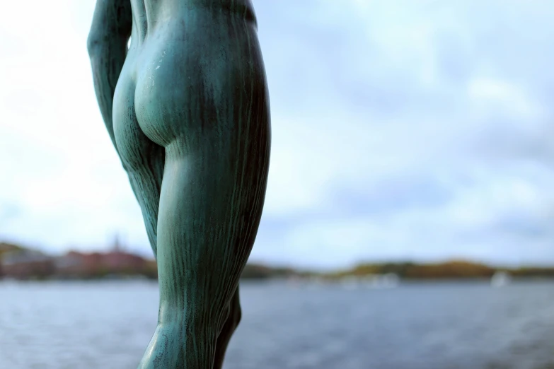 the bottom portion of a woman's torso statue by a body of water