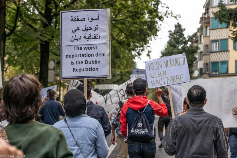 people holding signs in an open city, with many onlookers