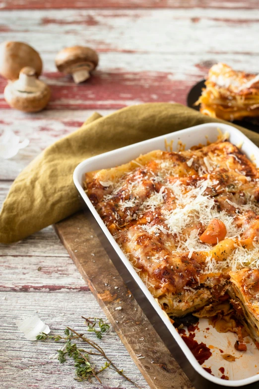 a dish of lasagna on a  board with mushroom sprinkles