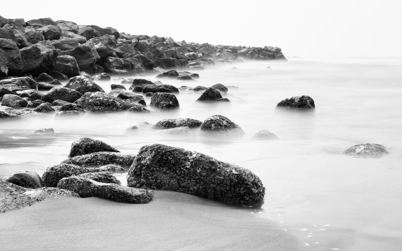 black and white po of a beach with rocks in the water