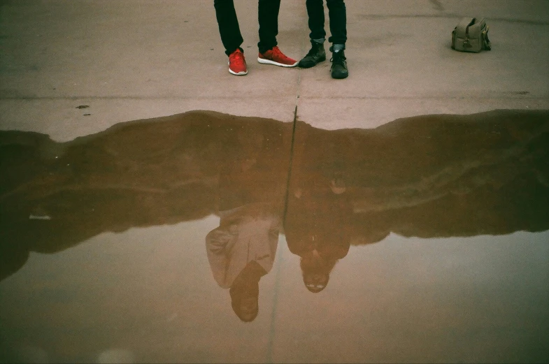 people standing on the street and reflection in water