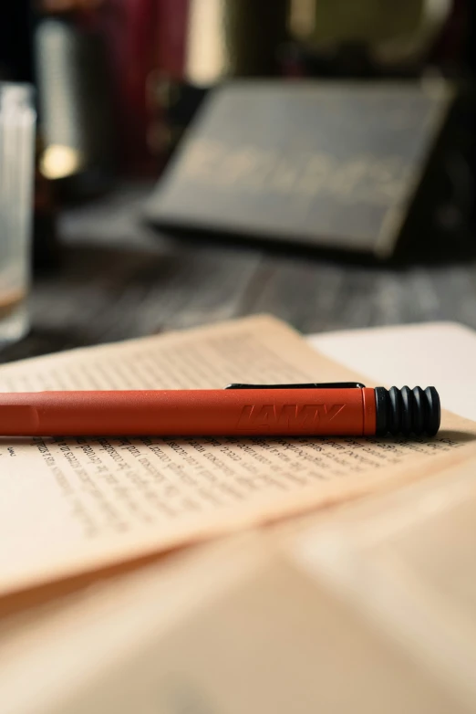 an orange pen resting on an open book