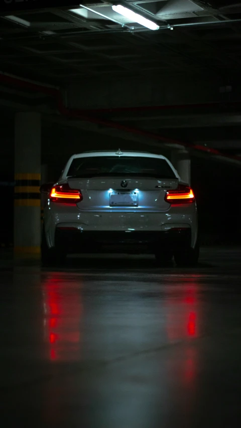 white car in dark garage at night with its ke lights on