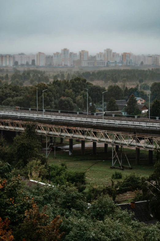 a bridge spanning the width of several intersecting roads with a city in the distance